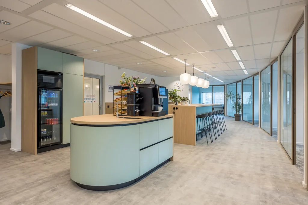 Moderne kantoorruimte met een koffiecorner en hoge tafels bij Zorggroep Haarlemmermeer.