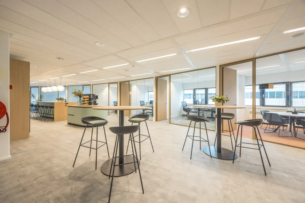 Moderne kantoorruimte van Zorggroep Haarlemmermeer met vergaderruimtes en hoge tafels.