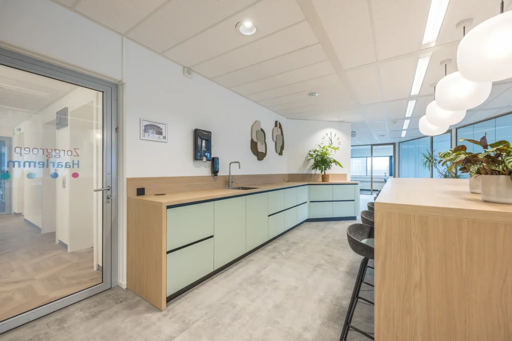 Moderne kantoorruimte van Zorggroep Haarlemmermeer met strakke keuken en stijlvolle inrichting.