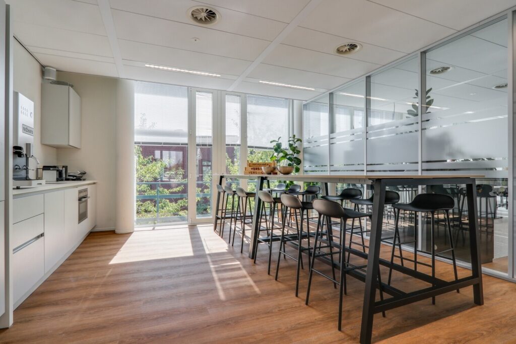 Moderne kantoorruimte met een vergadertafel, strakke keuken en veel natuurlijke lichtinval aan de Decuserstraat 89.