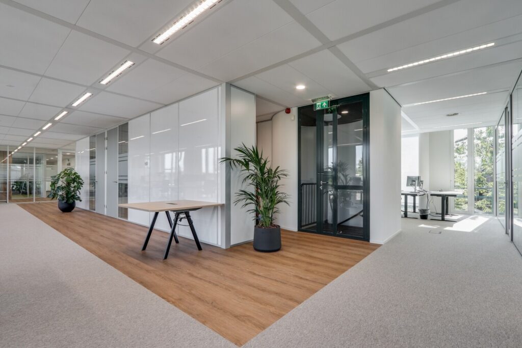 Modern kantoorinterieur met glazen wanden, houten vloer en groene planten bij de Decuserstraat 89-19.