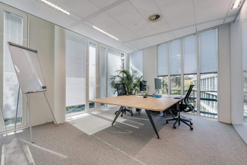 Modern kantoor met groot bureau, kantoorstoelen, een flip-over en veel natuurlijk licht bij Decuserstraat 89-20.