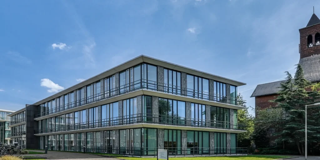 Modern kantoorpand aan de Decuserstraat 89-25 met grote ramen en naastgelegen kerkgebouw.