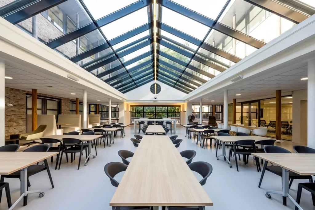 Ruime kantine met glazen dak en moderne zitplekken aan de Elspeterweg 22.