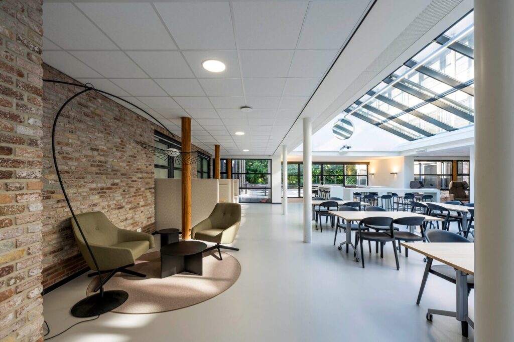 Moderne, lichte kantoorruimte met een zithoek en een glazen dak voor natuurlijke verlichting.