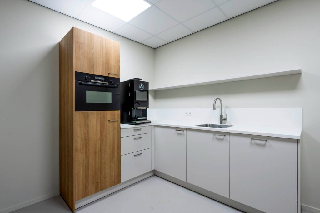 Moderne keuken met houten kast, ingebouwde oven, koffieapparaat en een werkblad met gootsteen.