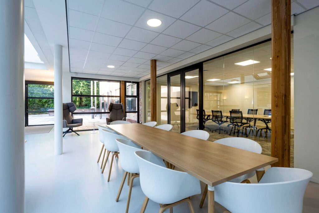 Moderne vergaderruimte met lange houten tafel en witte stoelen in een lichte, open kantooromgeving aan de Elspeterweg 22.
