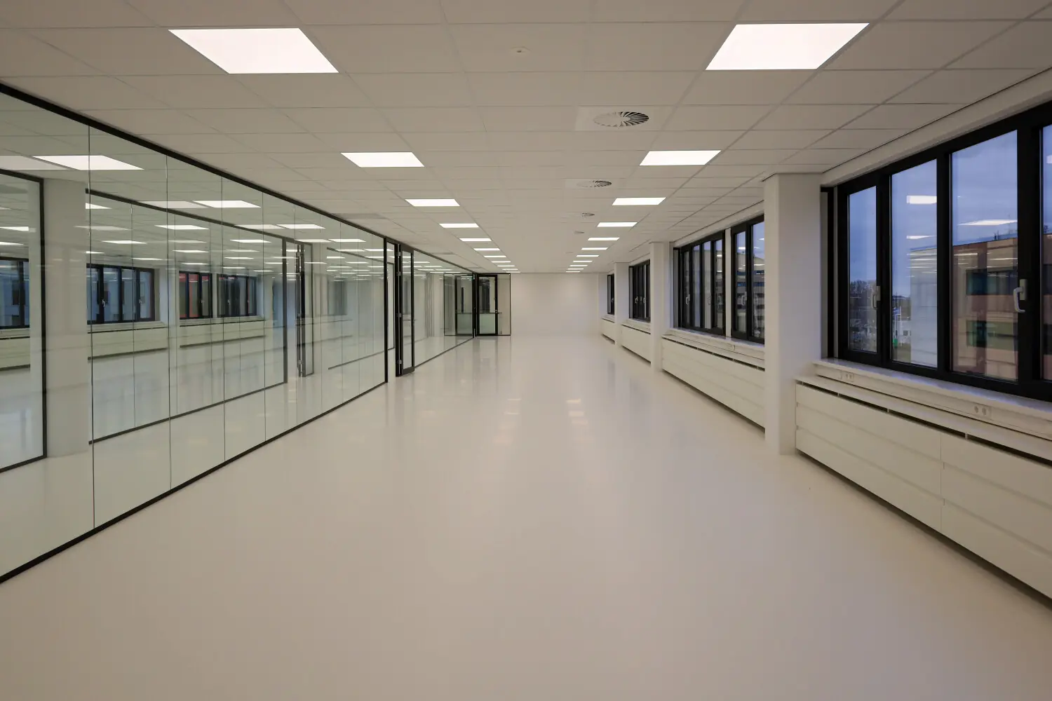 Leeg, modern kantoorinterieur met glazen wanden en grote ramen.