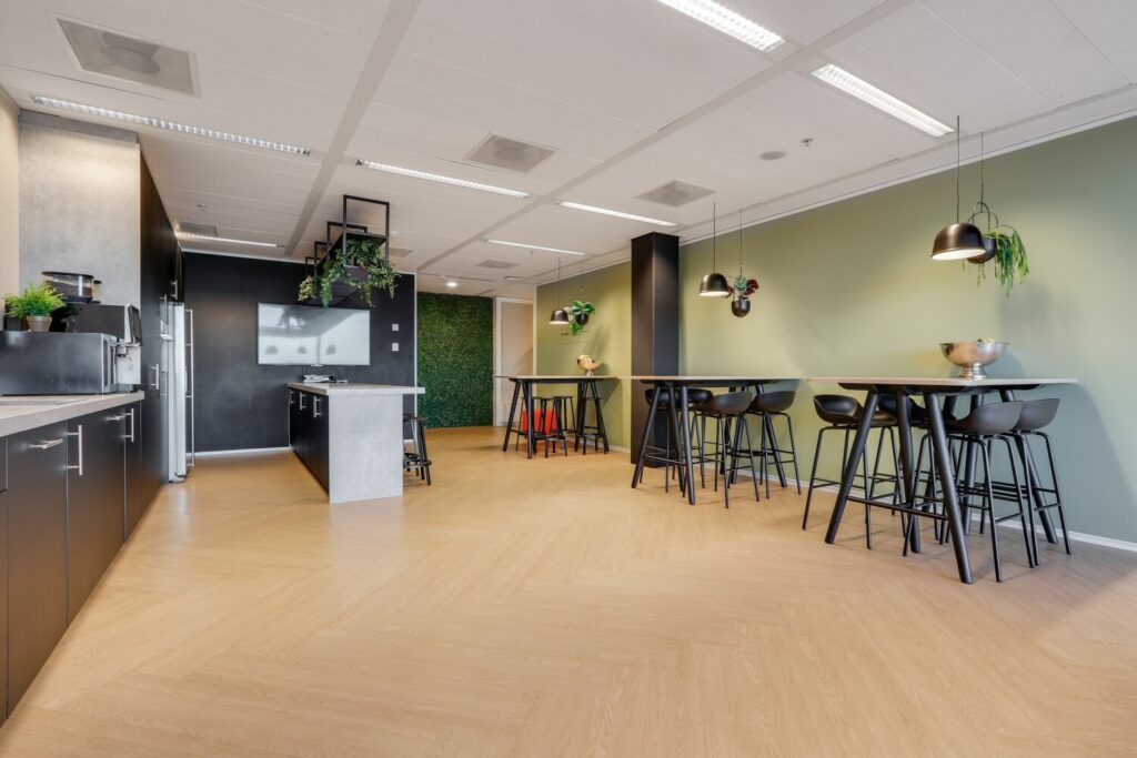Moderne kantoorruimte met hoge tafels, barkrukken en groene accenten aan de Gustav Mahlerlaan.