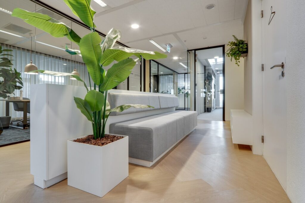 Moderne kantoorruimte met een witte plantenbak en een grijze banken bij de Gustav Mahlerlaan.