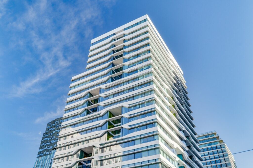 Moderne wolkenkrabber met witte en glazen gevel tegen een heldere blauwe lucht, bekend als het Gustav Mahler gebouw.