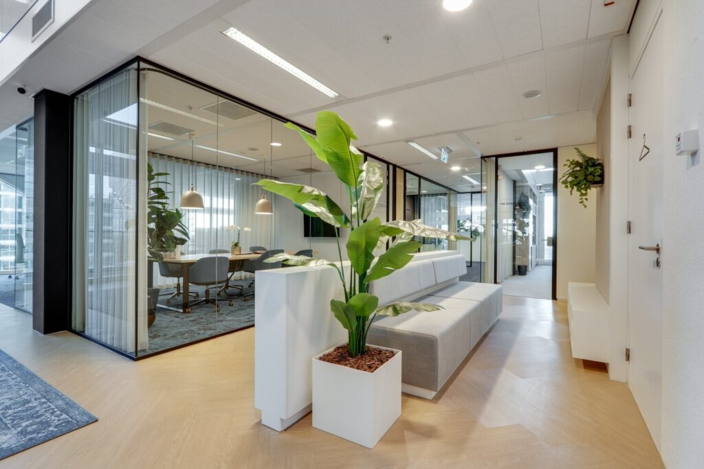 Moderne kantoorruimte met glazen vergaderruimte, comfortabele zitgelegenheid en groene planten op de Gustav Mahlerlaan.