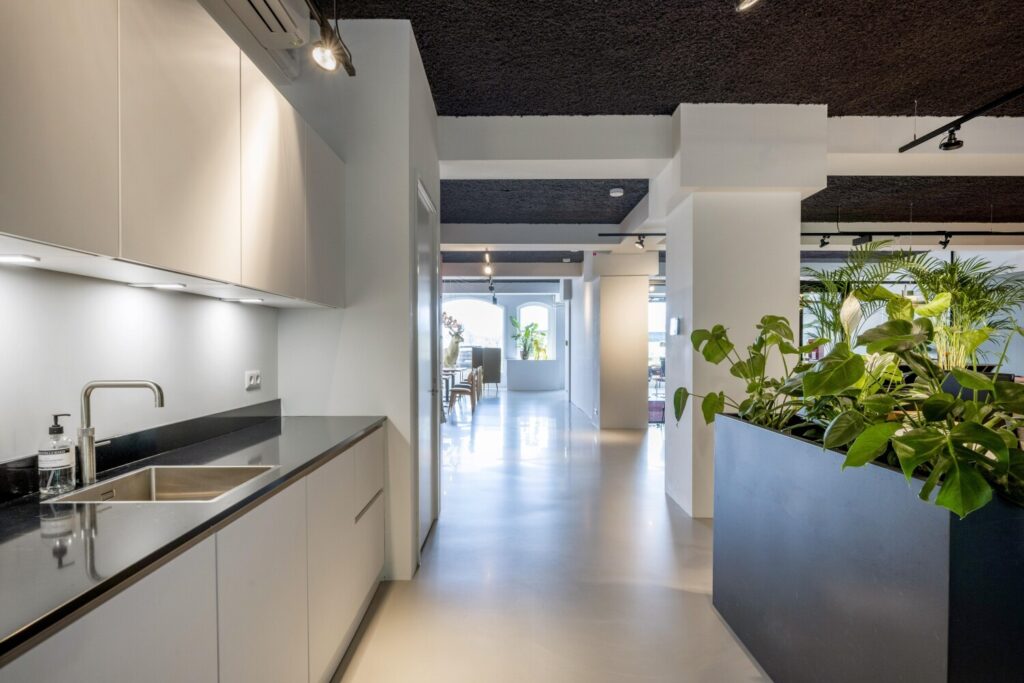 Moderne kantoorruimte met strakke keuken en veel groen.