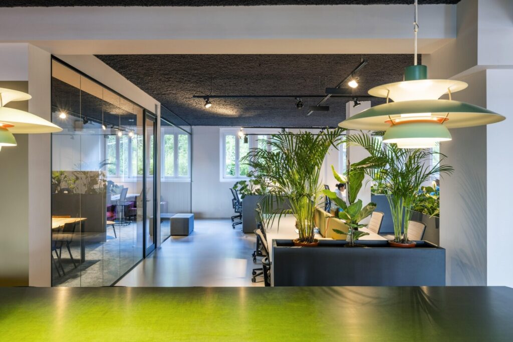 Modern kantoorinterieur met veel groen en glazen vergaderruimte.