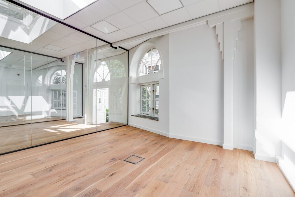 Licht, modern kantoorinterieur aan de Keizersgracht met glazen wanden en houten vloer.