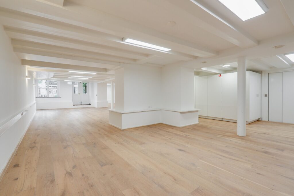 Leeg, modern kantoorinterieur met houten vloer en witgeschilderde muren aan de Keizersgracht 209.