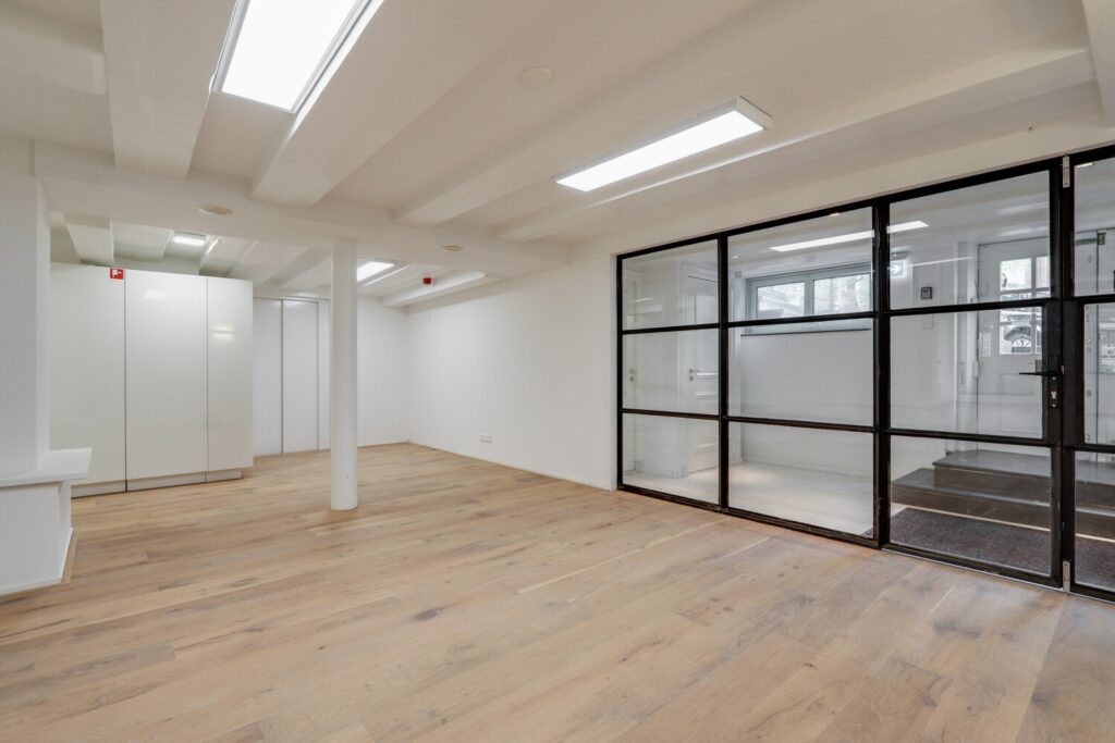 Licht, modern kantoorinterieur aan de Keizersgracht 209 met glazen wanden en houten vloer.