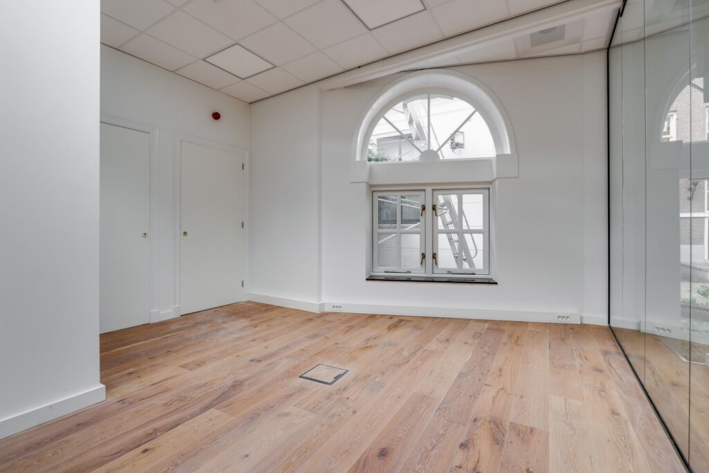 Licht kantoorruimte in Amsterdam met houten vloer, afgeronde raampartij en glaswand aan de Keizersgracht 209.