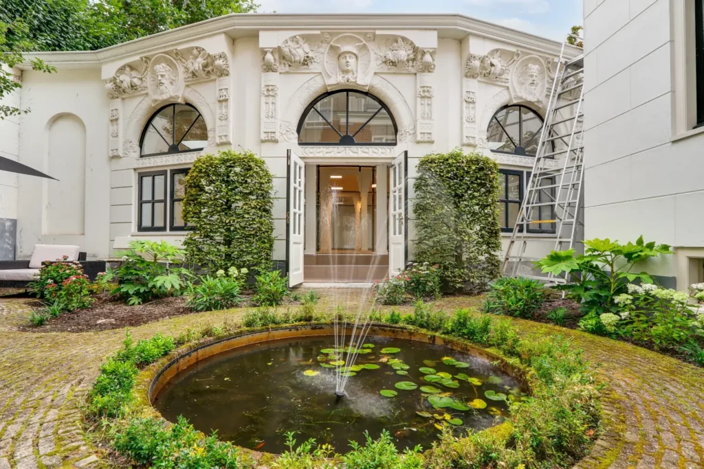 Elegante tuin met fontein voor een historisch gebouw aan de Keizersgracht 209 met sierlijke geveldecoraties.