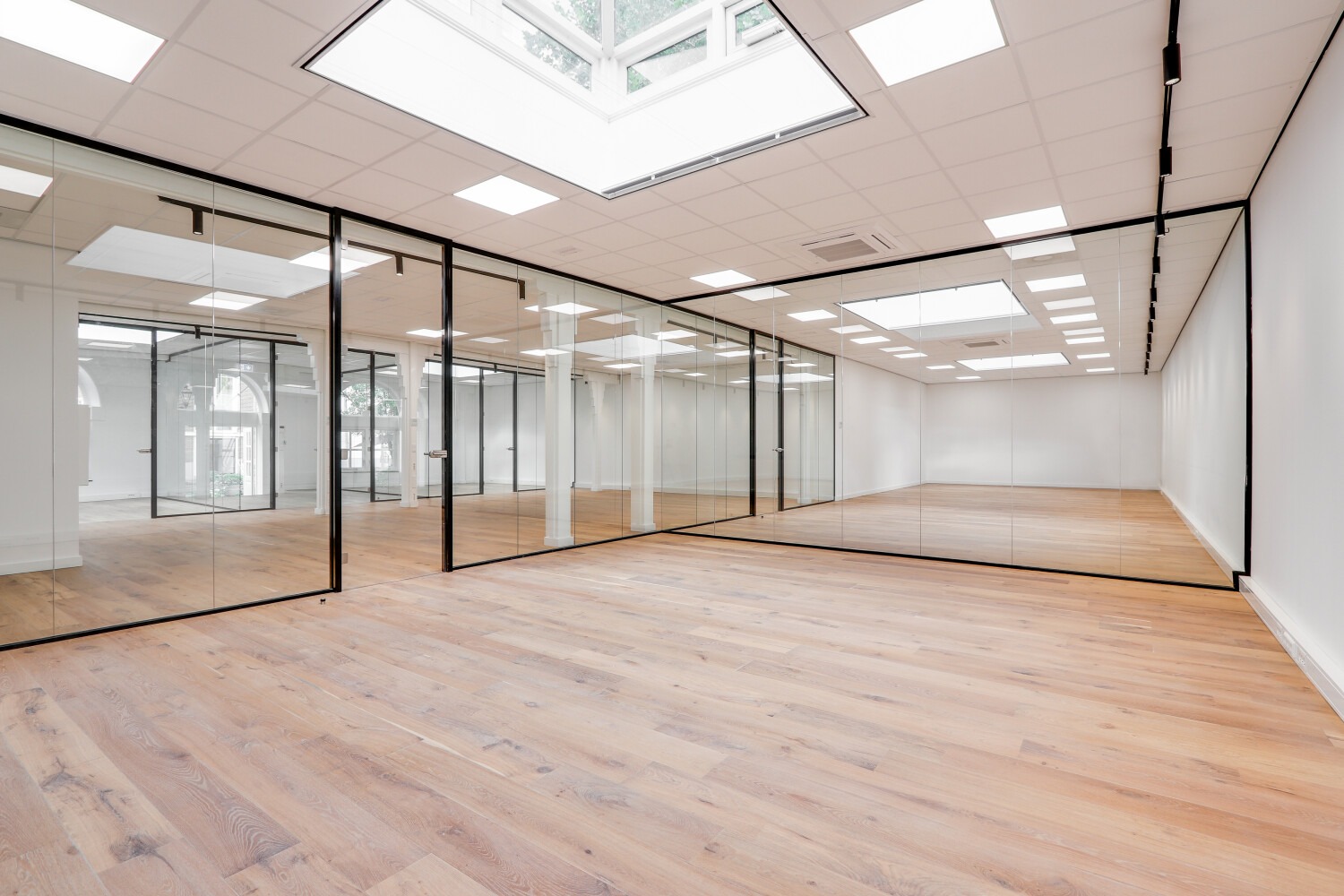 Lichte, ruime kantoorruimte aan de Keizersgracht met glazen wanden en houten vloer.