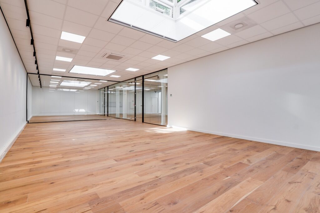 Licht, modern kantoorinterieur aan de Keizersgracht 209 met houten vloer en glazen wanden.