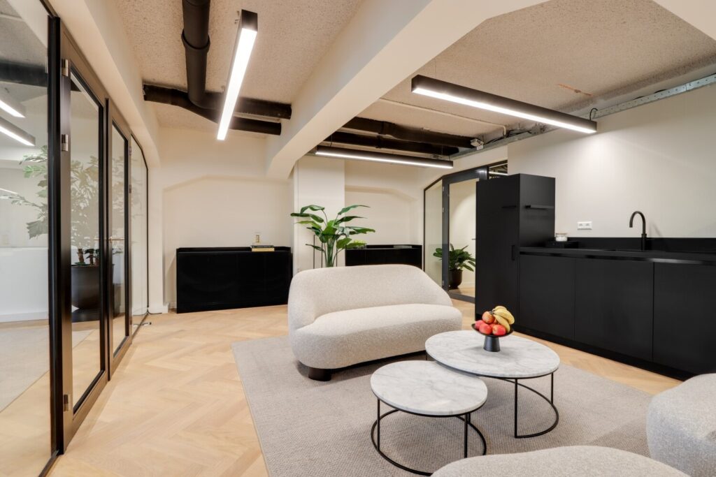 Moderne kantoorruimte met een strak interieur, comfortabele zithoek en minimalistische keuken.