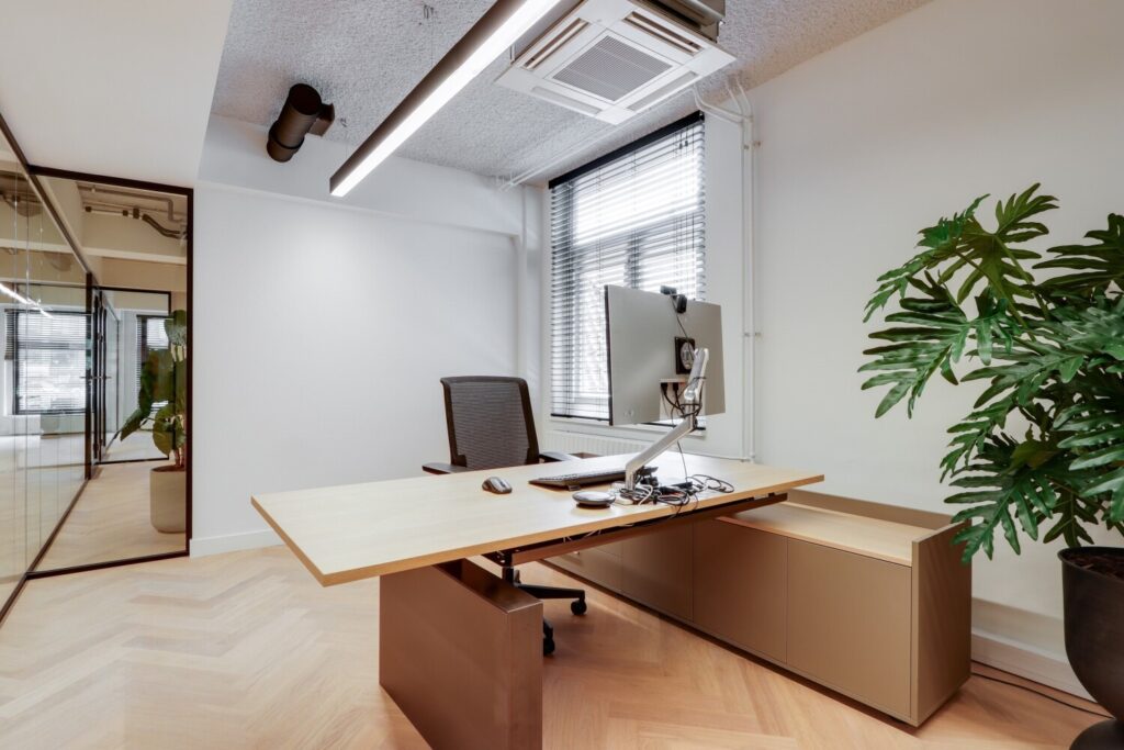 Moderne kantoorruimte met een elegant bureau, ergonomische stoel en decoratieve plant, gelegen aan de Amsterdamse Singel.