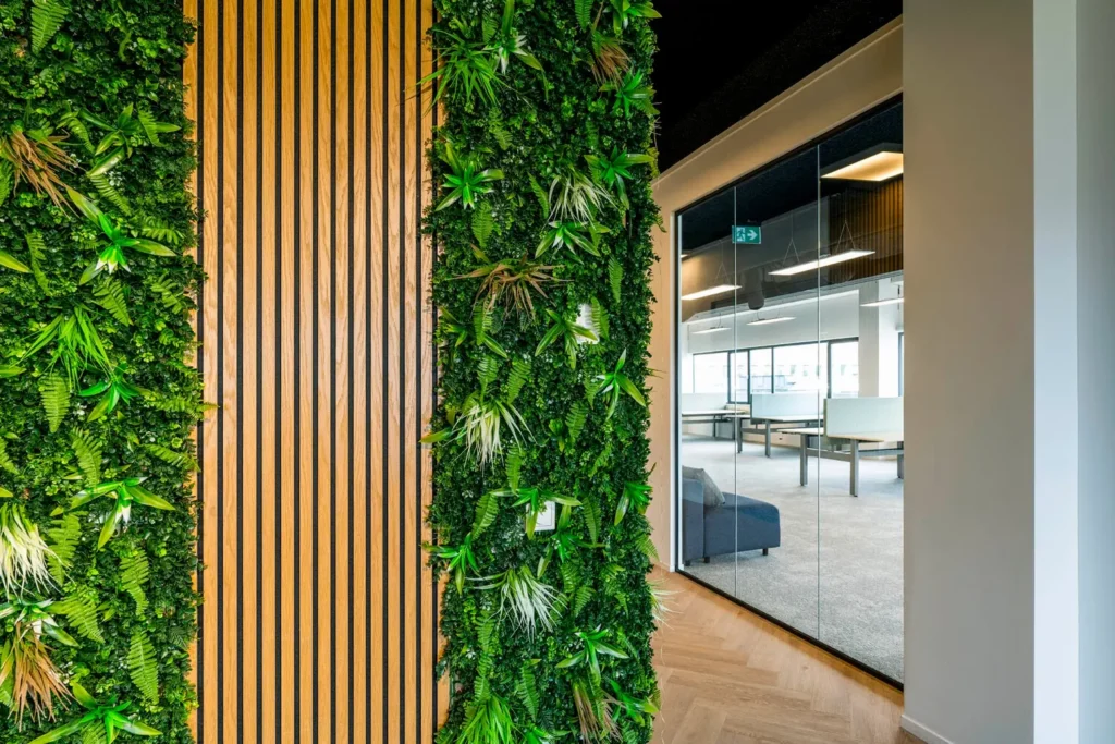 Groene plantenwand en houten panelen in een modern kantoorinterieur aan de Transformatorweg 76.