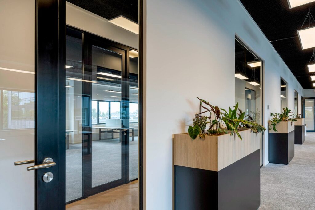 Moderne kantoorruimte met glazen deuren en plantenbakken in de gang op Transformatorweg 76.