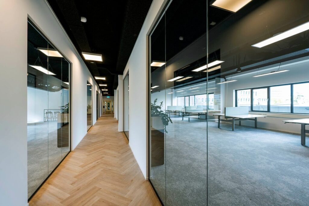 Moderne kantoorhal met glazen wanden en uitzicht op een ruime werkruimte aan de Transformatorweg 76.