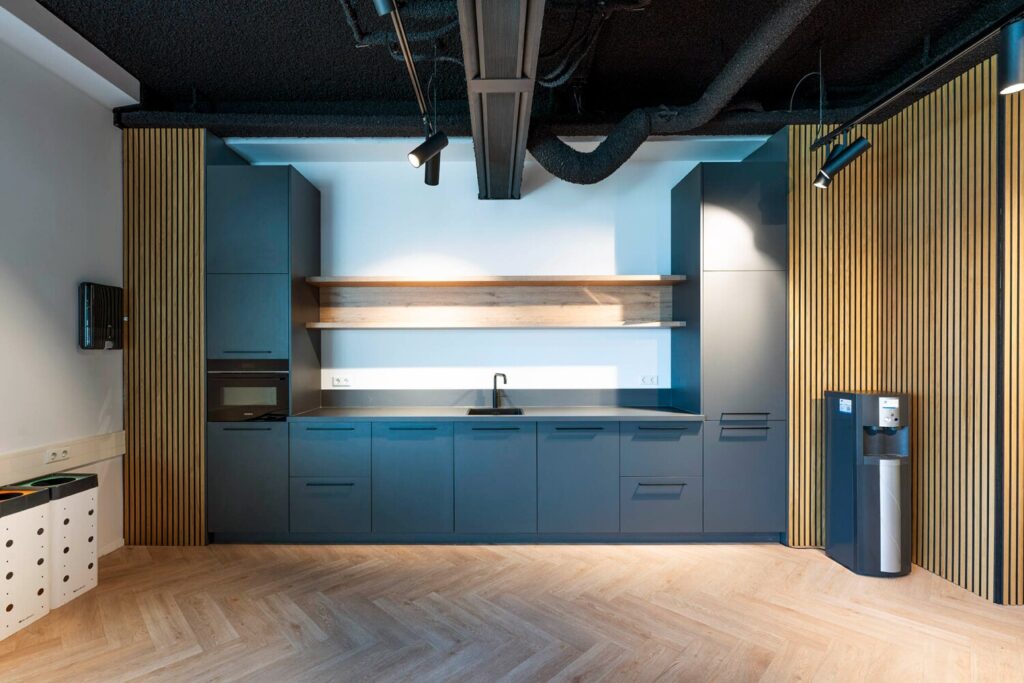 Moderne kantoorkeuken met strakke zwarte kasten, een ingebouwde magnetron en houtaccenten aan de Transformatorweg 76-26.