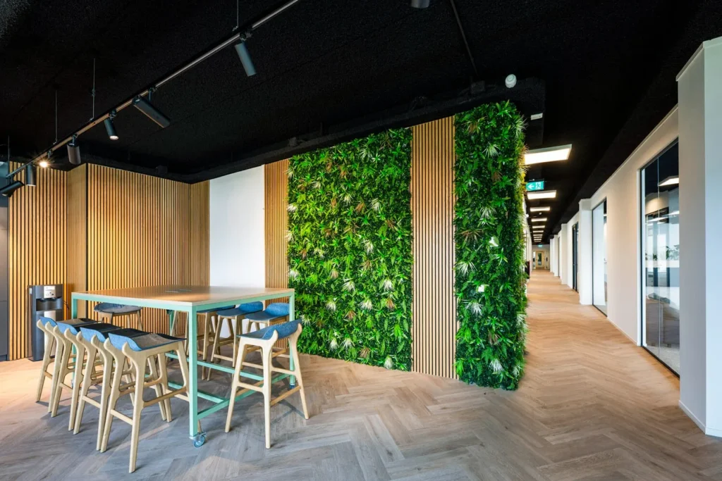 Moderne kantoorruimte met een hoge tafel en barkrukken naast een groene plantenwand.