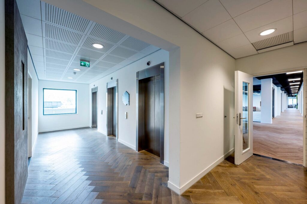 Moderne kantoorruimte met liften en een gang op Transformatorweg 76-30.