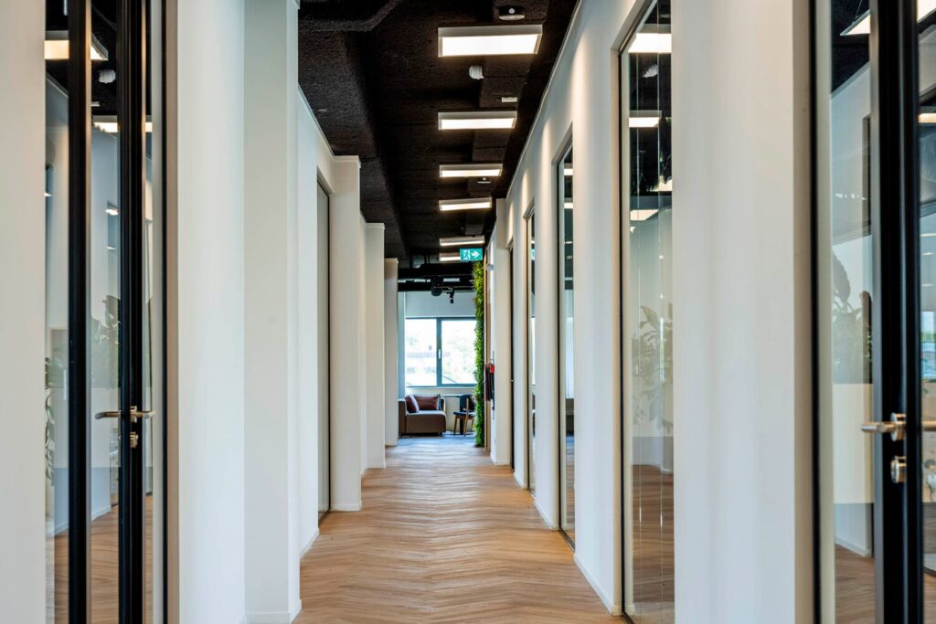 Een moderne kantoorhal met glazen deuren en houten vloeren aan de Transformatorweg 76.