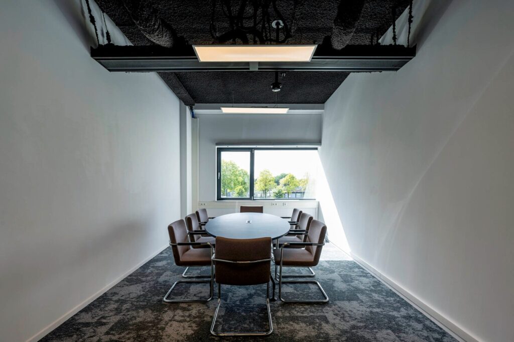 Een moderne vergaderruimte met een ovale tafel, omringd door stoelen, gelegen aan de Transformatorweg 76.