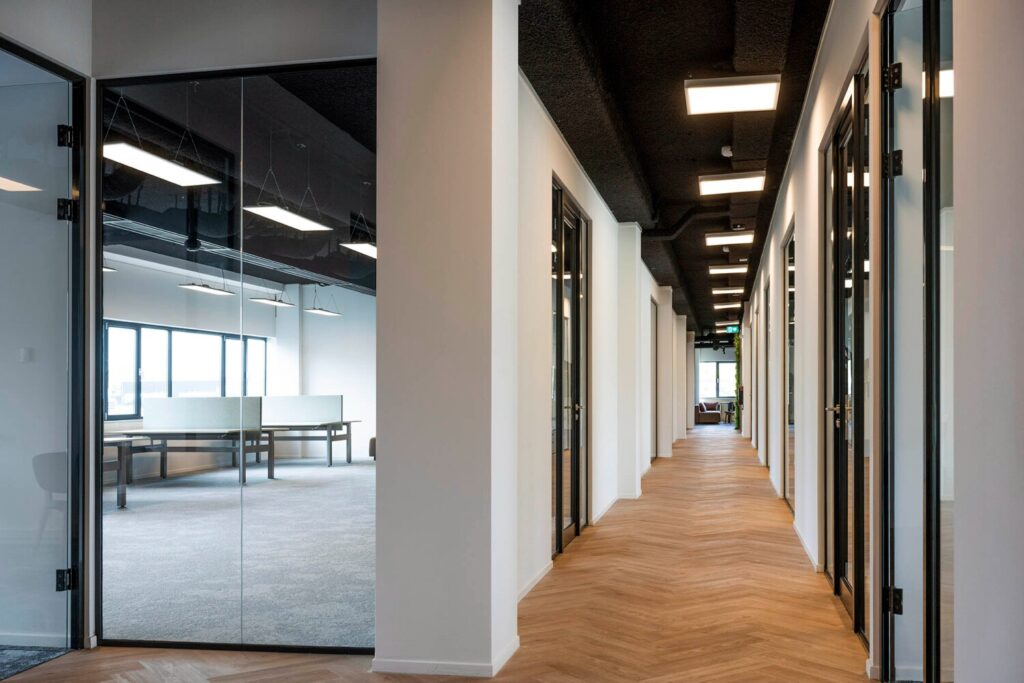 Heldere kantoorruimte met glazen deuren en een lange, houten gang op Transformatorweg 76-8.