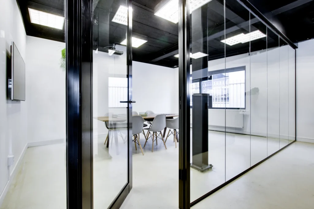 Een moderne vergaderruimte met glazen wanden en stijlvolle stoelen in een strak kantoorinterieur.