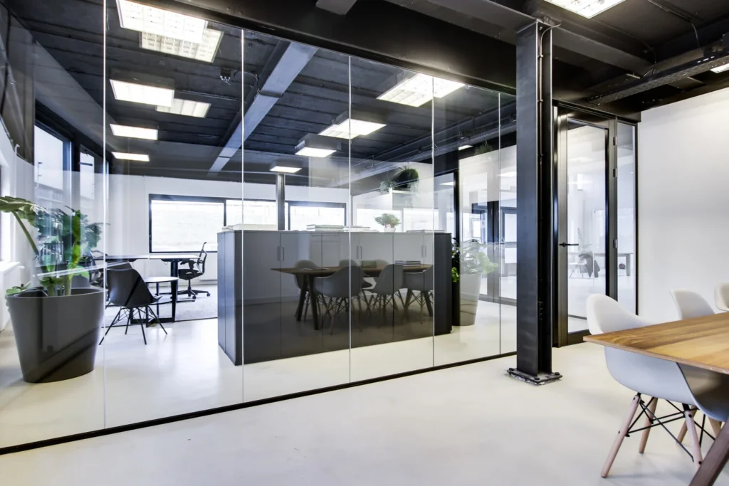 Modern kantoorinterieur met glazen wanden, strakke meubels en veel natuurlijk licht.