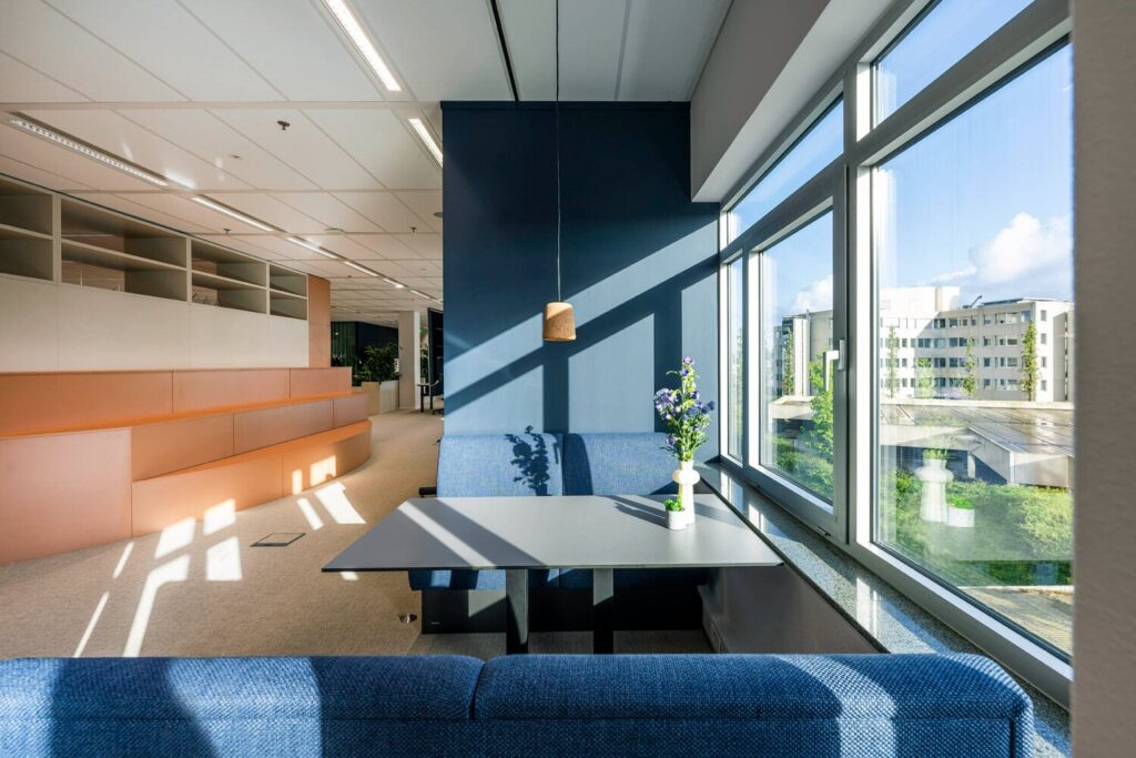 Modern ingerichte kantoorruimte aan de Winthontlaan met blauwe banken, grote ramen en een uitzicht op de stad.