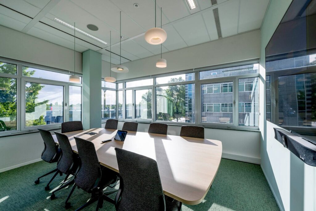 Vergaderruimte met een grote tafel en stoelen bij Winthontlaan 17 met veel daglicht door grote ramen.