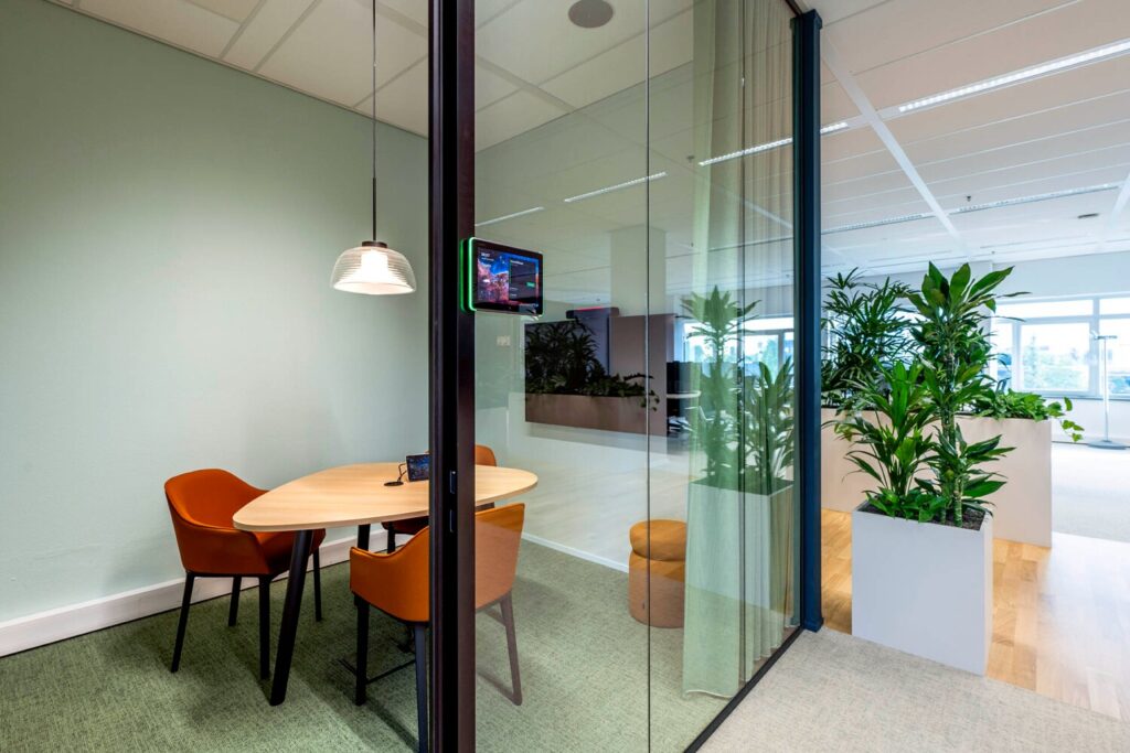 Moderne vergaderruimte met glazen wanden en groene planten bij Winthontlaan 21.