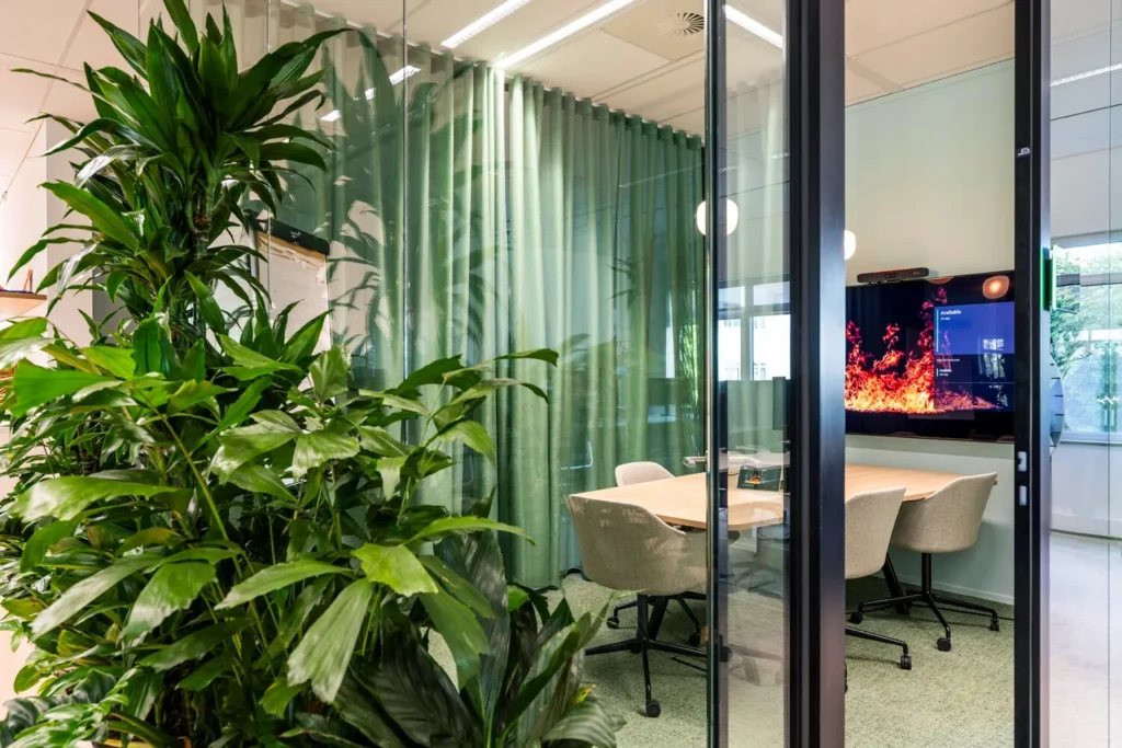 Moderne vergaderruimte met groene planten en een groot scherm aan de Winthontlaan 6.