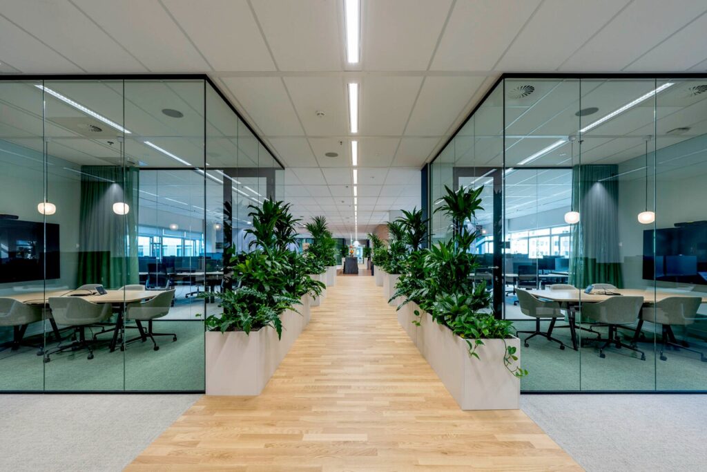 Moderne kantoorruimte op de Winthontlaan 8 met glazen vergaderruimtes en groene planten.
